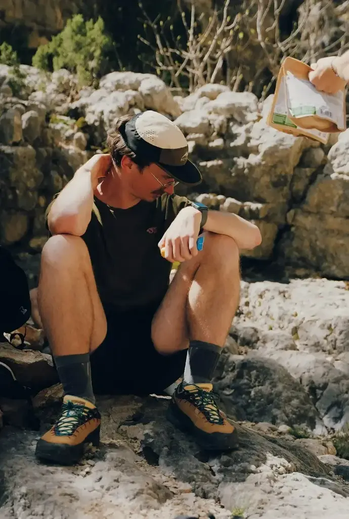 Homme assis contre un rocher faisant une pause après une randonnée