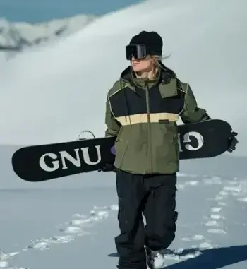 Surfeur tenant sa planche sur une piste de ski