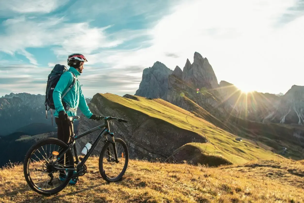 Jeune homme en vélo faisant une pause pour admirer un paysage montagneux baigné par la lumière du soleil